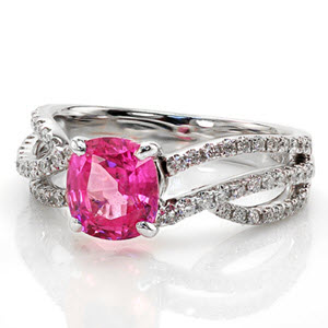 Custom pink sapphire engagement ring in Austin. This unique, micro pave split shank engagement ring features flowing diamond bands and a bright pink cushion cut sapphire center
